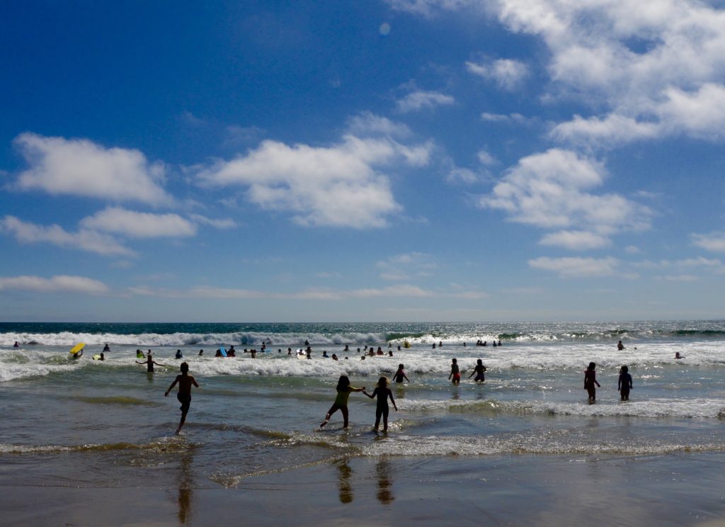 Children play in the waves of the Pacific Ocean at Santa Monica Beach